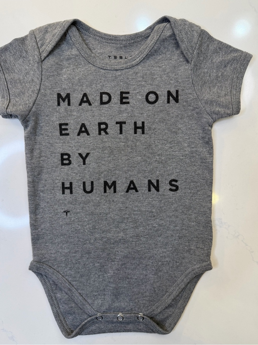 Tesla Grey Baby One-Piece with "Made on Earth by Humans" Text